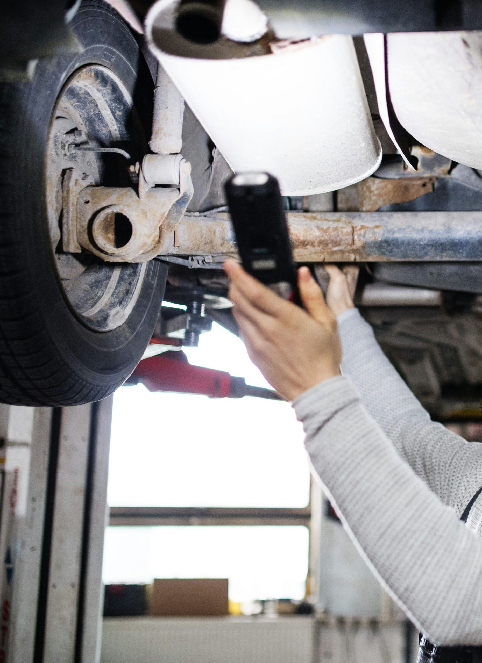 specialist in exhaust repairs main with a light shining on car exhaust