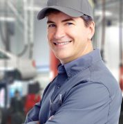 car mechanic smiling, wears grey uniform