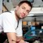 car mechanic wearing white holding a tool